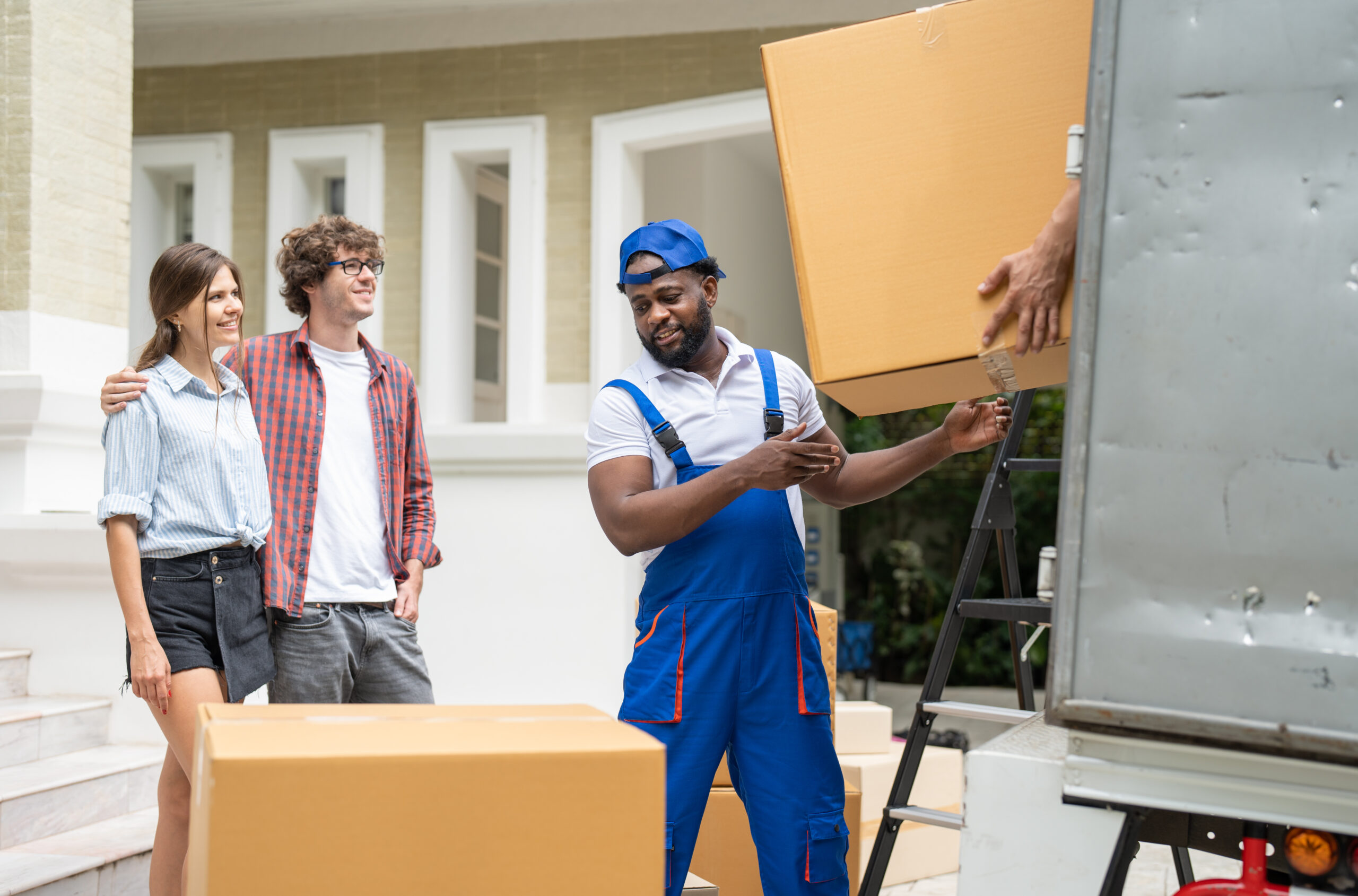 Man movers worker in blue uniform unloading cardboard boxes from truck.Professional delivery and moving service.